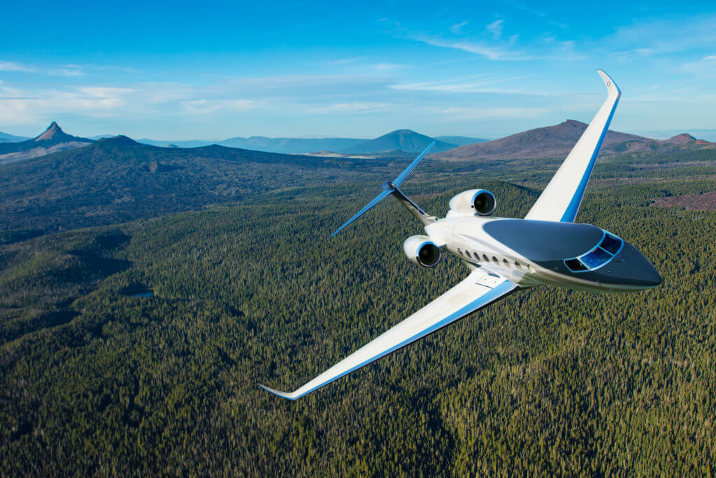 Gulfstream G800 private jet in a right bank flying over green forest 